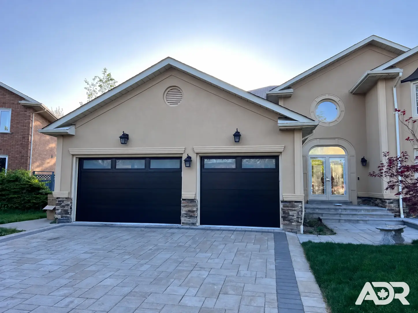 Black double and single garage doors with top windows on a stucco house