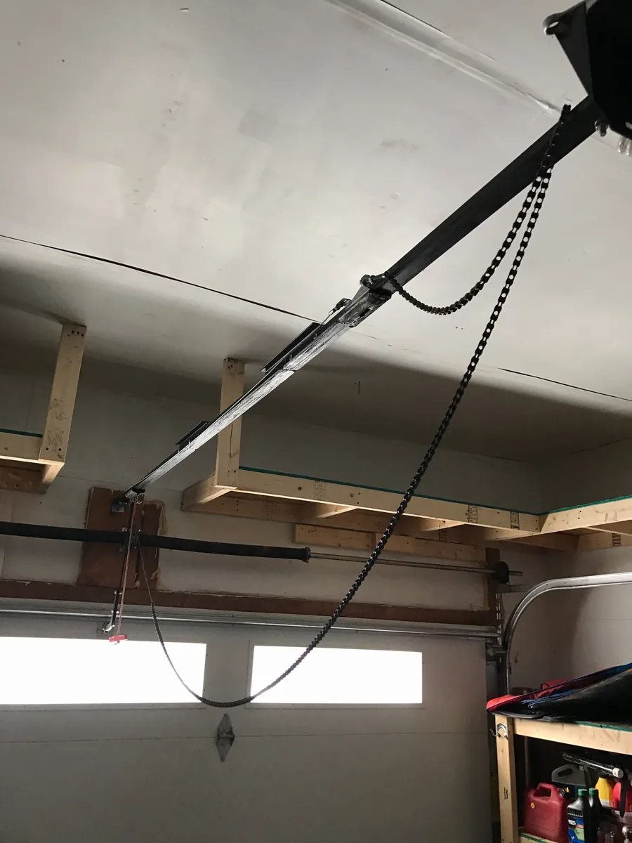 Loose garage door opener chain hanging below the rail inside a garage.