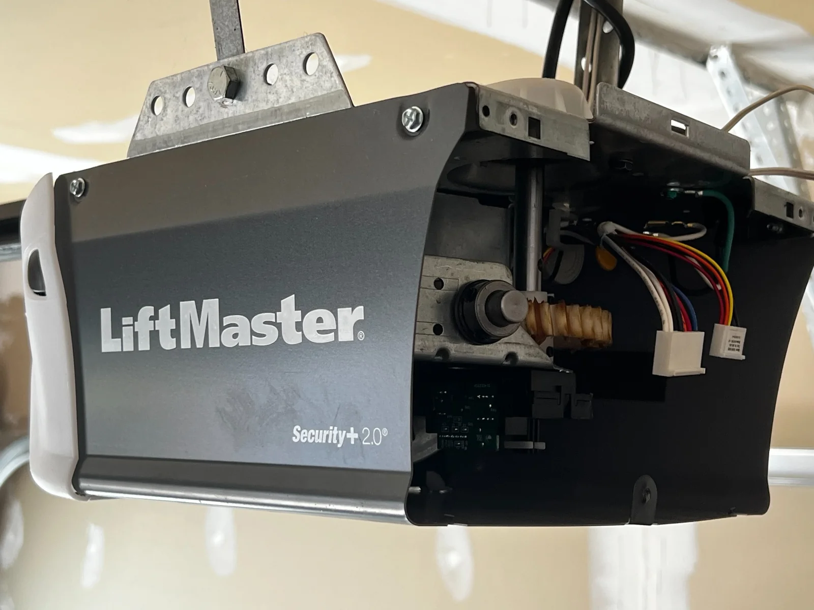 LiftMaster garage door opener with its side cover removed, exposing the drive mechanism and wiring.