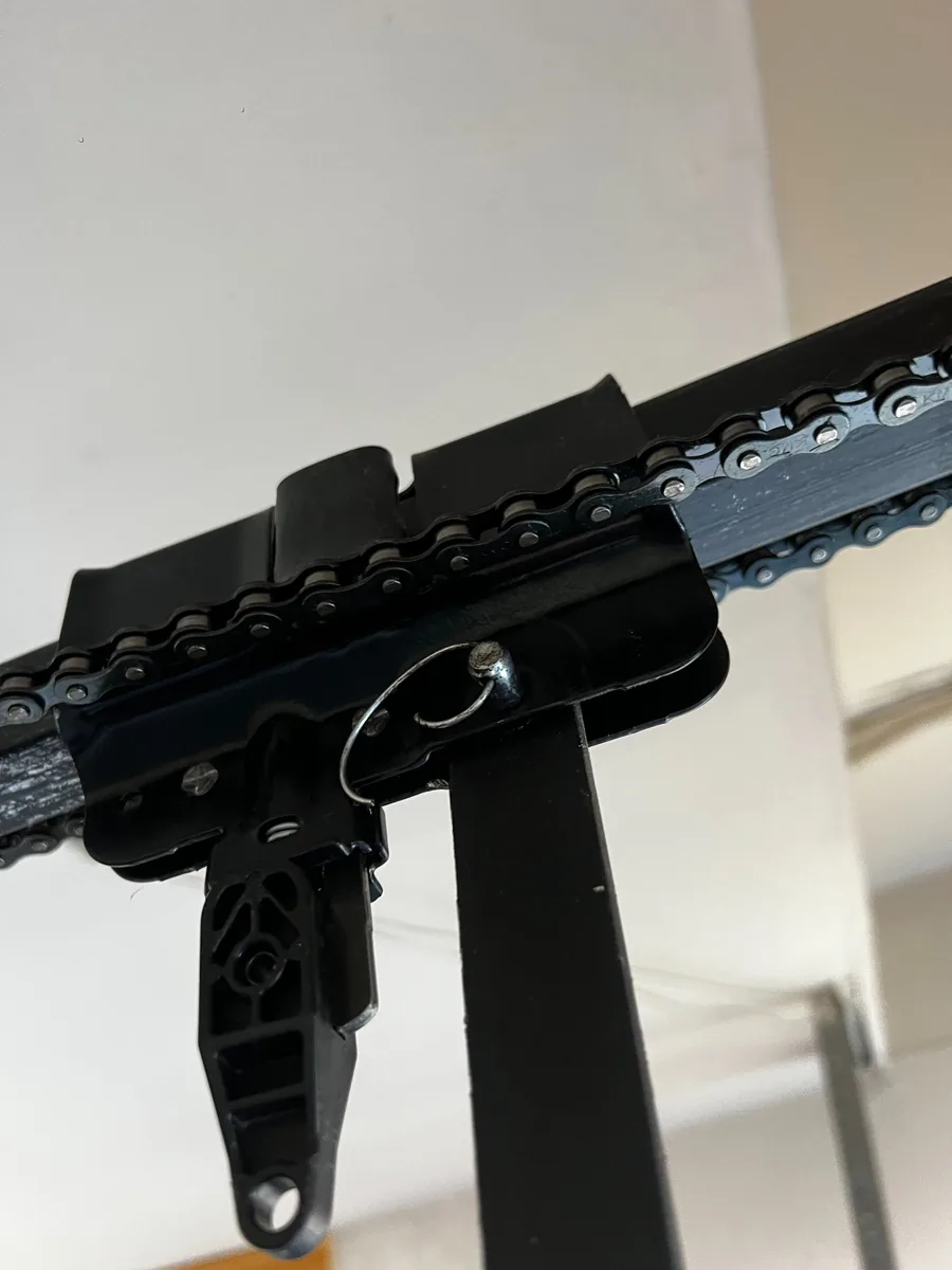 Close-up of a garage door opener trolley on the rail, with the chain and door arm connection visible.