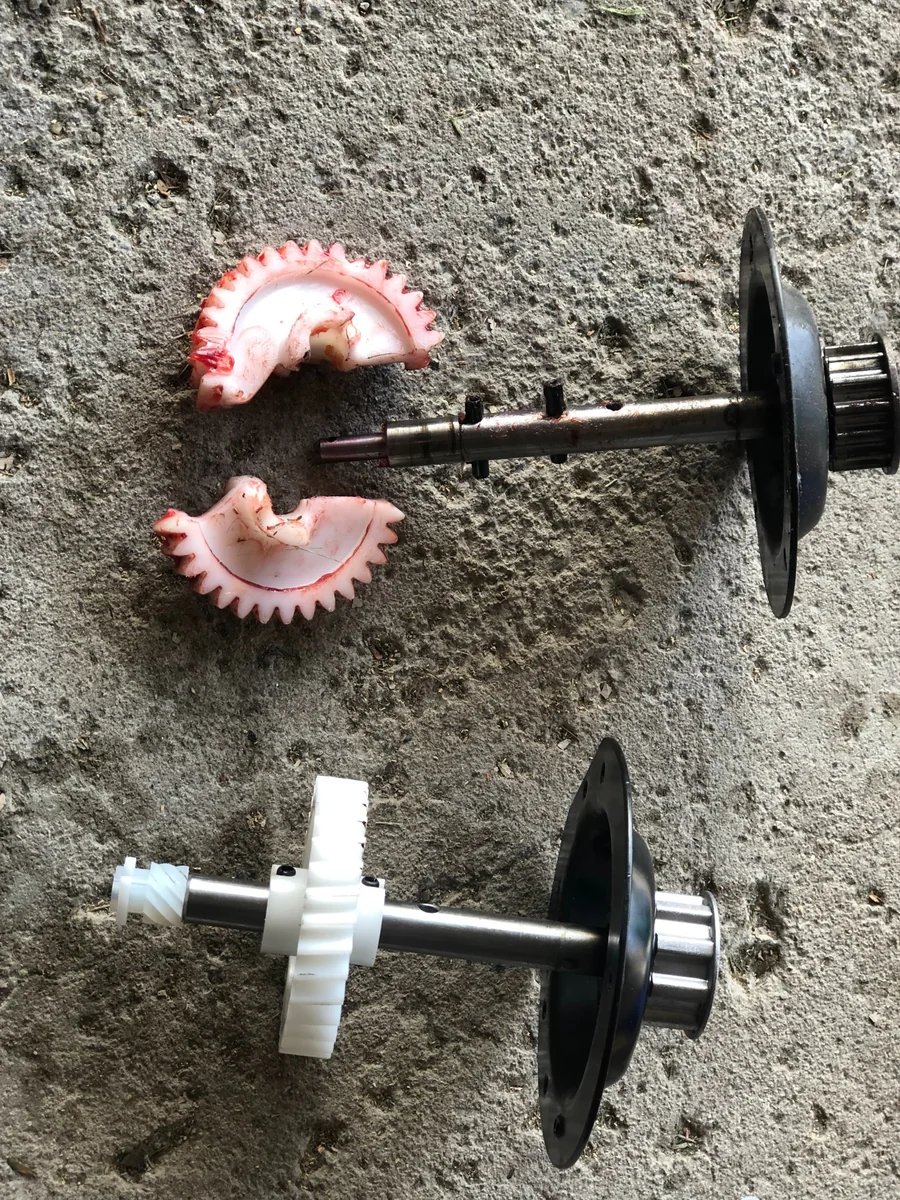 Broken plastic opener gear beside an intact gear and shaft assembly.