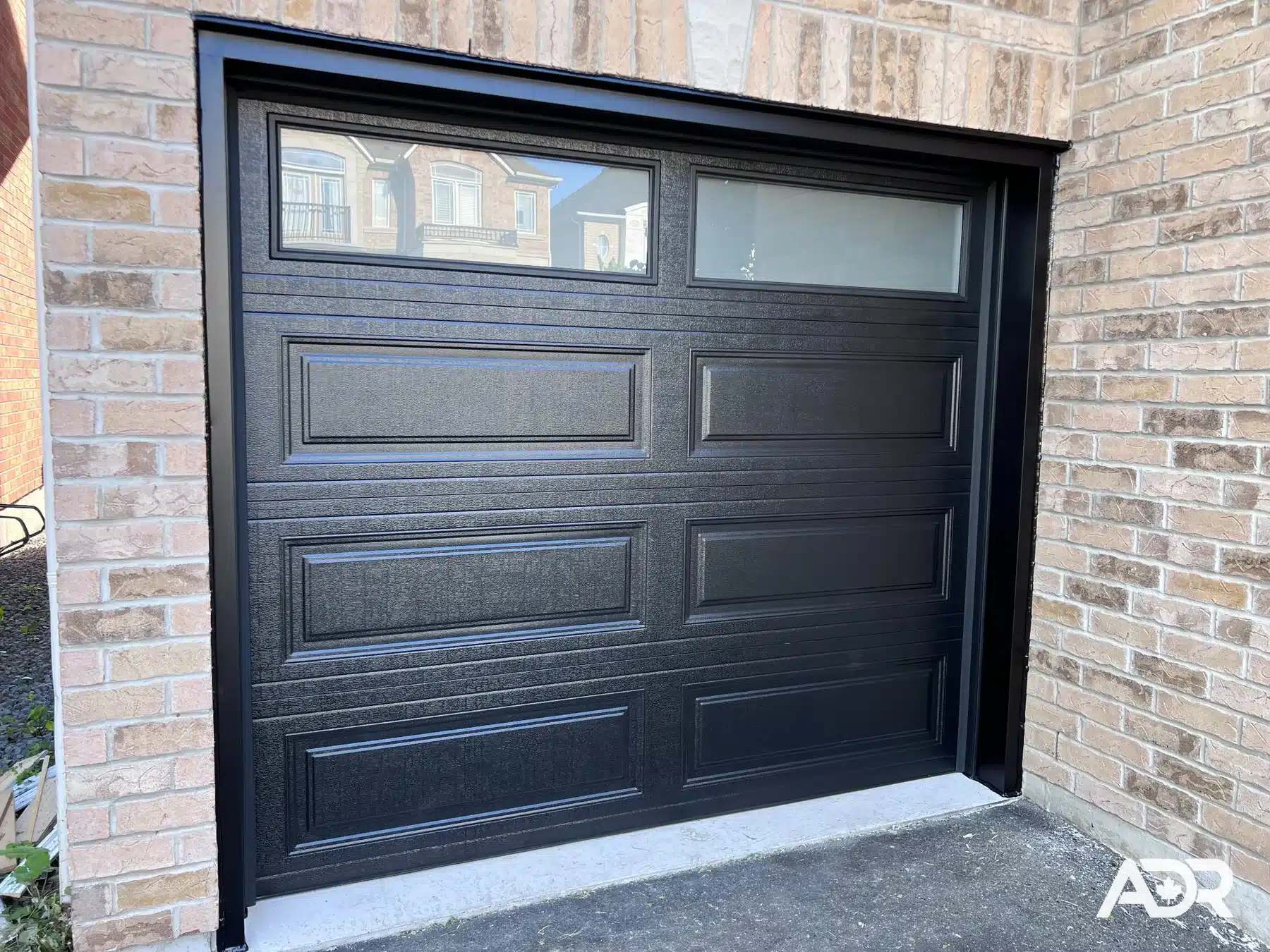 Black single garage door with top windows after installation