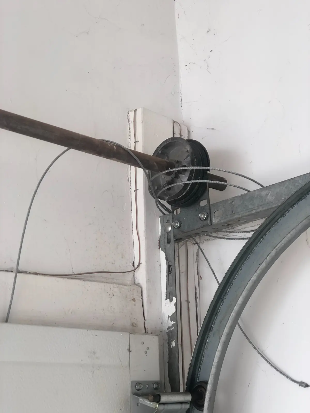 Loose cable at the garage door drum Loose garage door cable around a cable drum beside the upper track