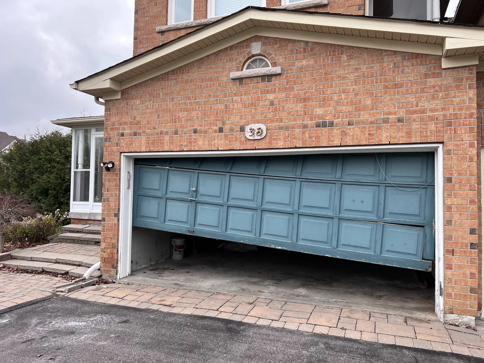 Crooked double garage door hanging unevenly during a cable repair inspection in the GTA
