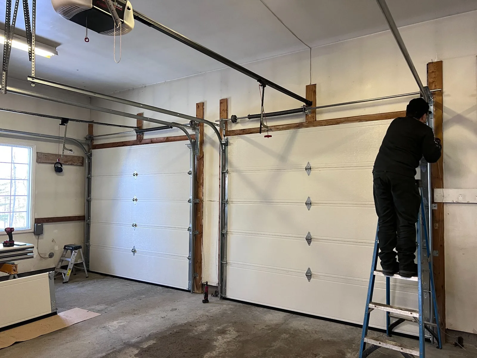 ADR technician inspecting garage door lifting hardware during residential cable repair service