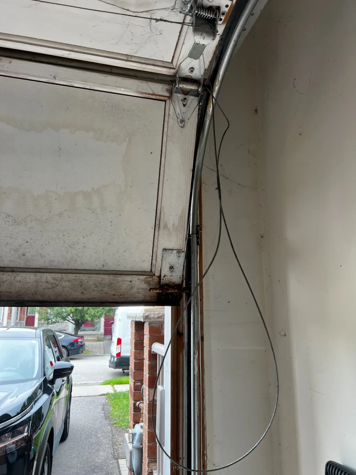 Loose garage door cable hanging beside the track after coming off the lifting system