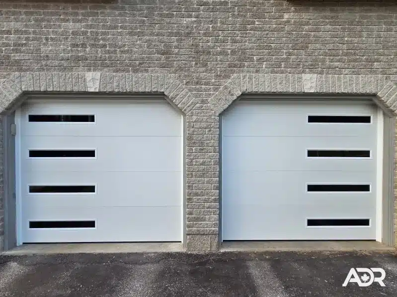 Two modern white garage doors with offset horizontal windows after installation